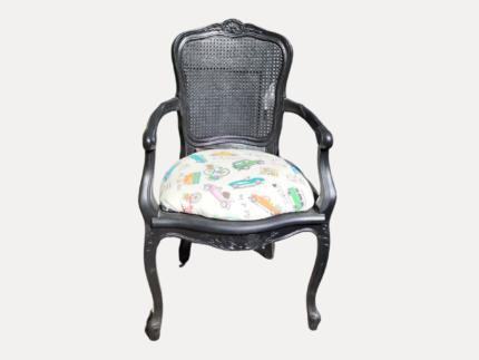 Fauteuil en rotin noir avec assise rembourrée imprimée colorée, disponible à la location.