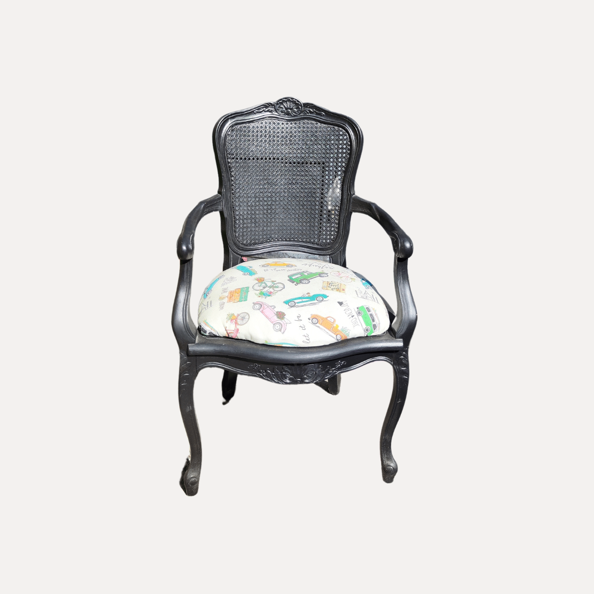 Fauteuil en rotin noir avec assise rembourrée imprimée colorée, disponible à la location.