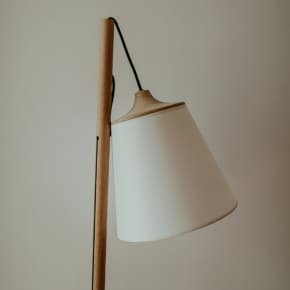 Lampadaire en bois naturel avec abat-jour blanc minimaliste dans un intérieur épuré.